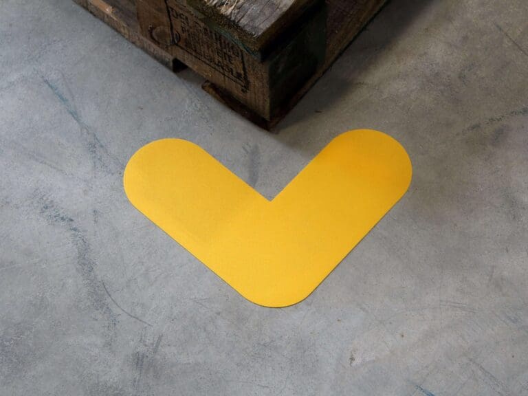 Keltainen v:n muotoinen Lattiaopaste merkintäteipit betonilattialla.