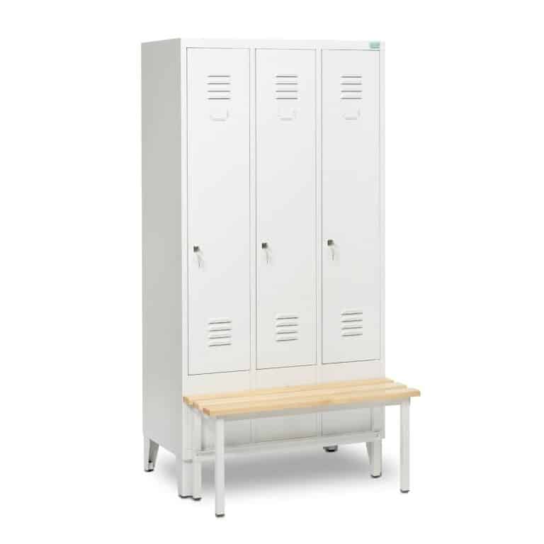 Kolme valkoista metallipukukaappia, joissa tuuletusraot ja puinen penkki, eristetty valkoisella pohjalla.