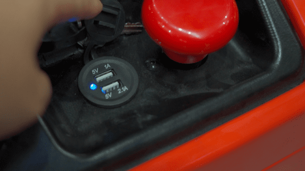 Lähikuva USB-latausportista, jossa on valaistu sininen merkkivalo, joka sijaitsee punaisen nupin vieressä Pinoamistrukki WSA 1600KG -pinnalla.
