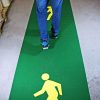 Green pedestrian walkway floor marking tape with yellow walking-person symbol