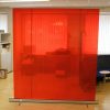 Red translucent PVC welding curtain material on a freestanding welding screen