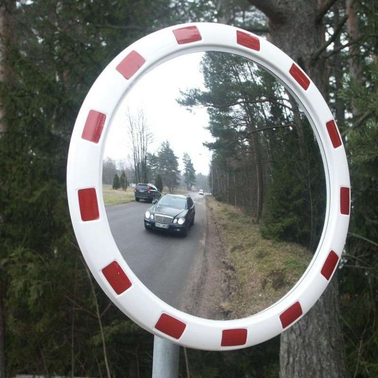 Round convex traffic mirror with red-and-white frame mounted beside a road