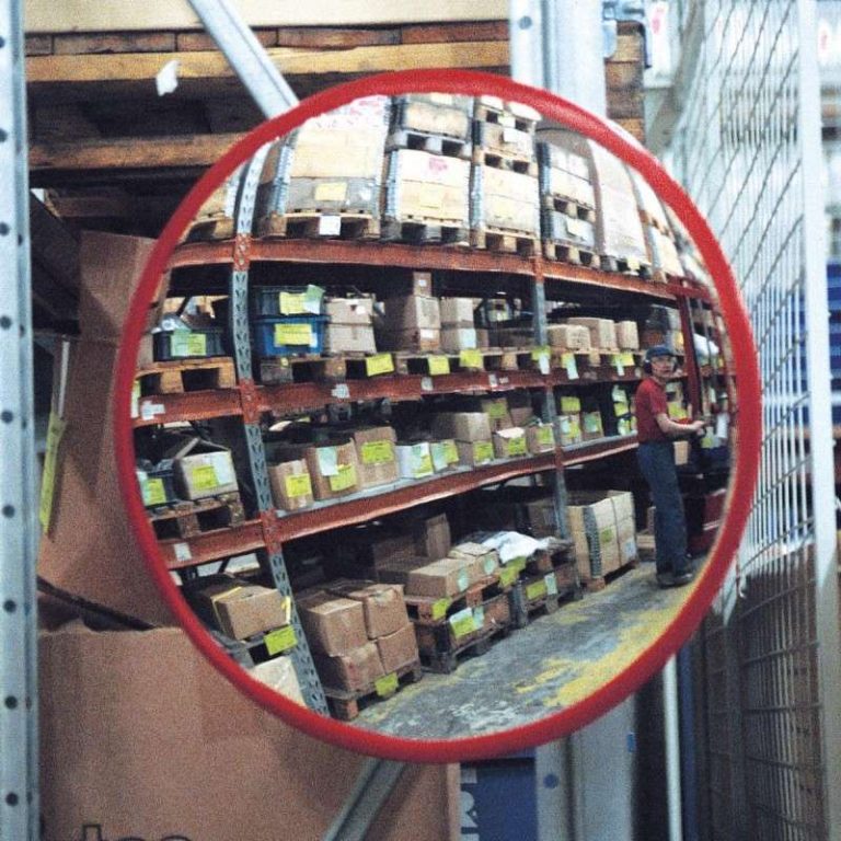 Round industrial traffic mirror with red-orange frame in a warehouse aisle