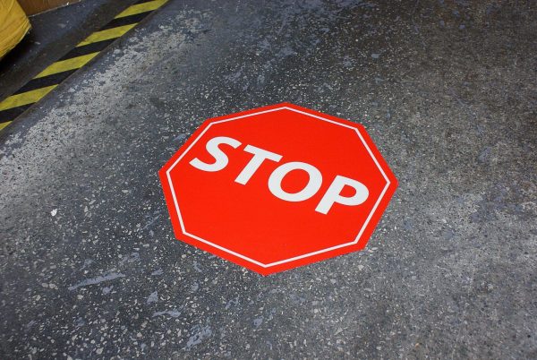STOP‑golvdekal 430 mm på betonggolv – tydlig golvmarkering i rött med vit text