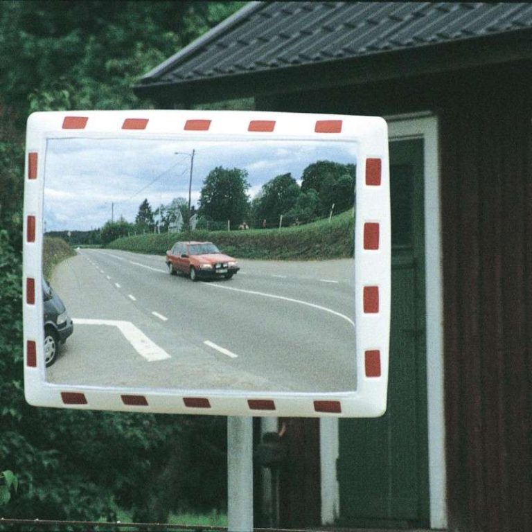 Trafikspegel i slagfast akryl med rödvit ram vid en skymd utfart