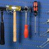 Hand tools hanging from hooks on a blue perforated tool panel